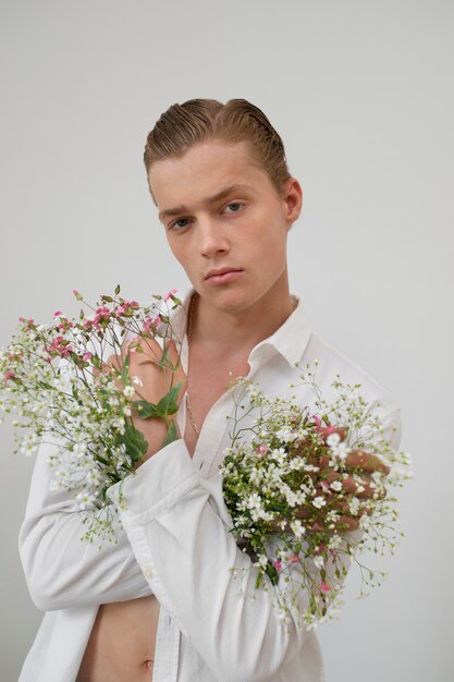 Hombre con flores posando plano medio