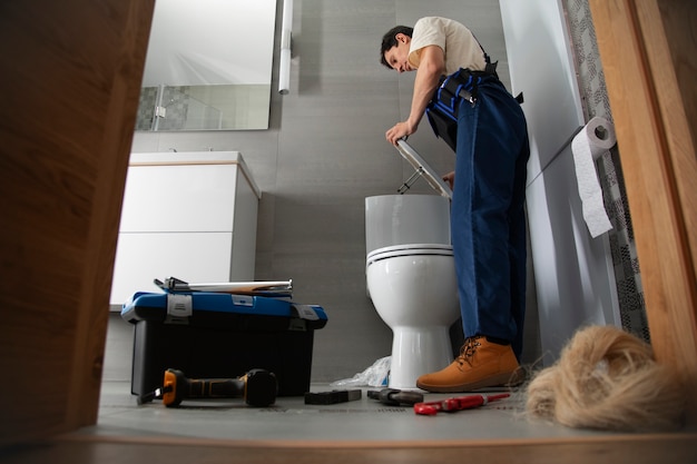 Foto gratuita hombre fontanero trabajando para arreglar problemas en la casa del cliente