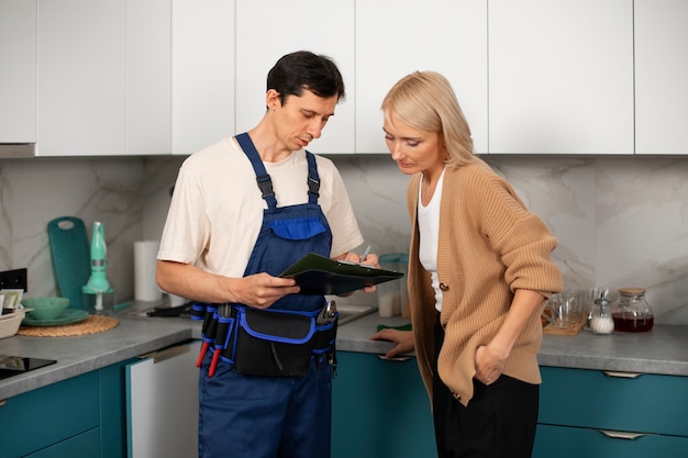 Hombre fontanero trabajando con el cliente para arreglar problemas de cocina