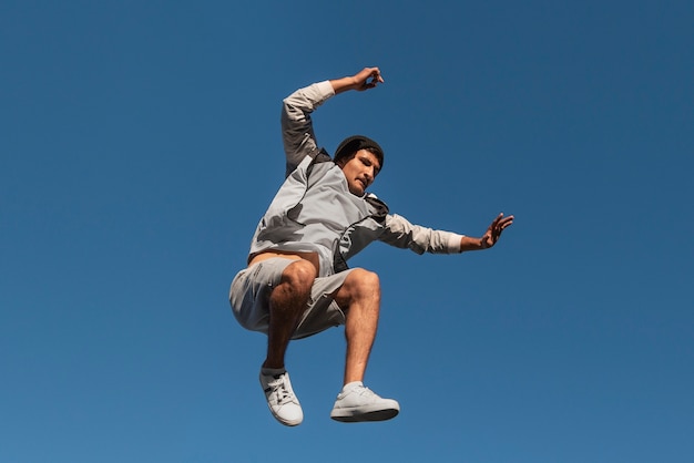 Hombre en forma de ángulo bajo saltando al aire libre