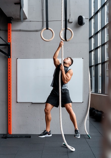 Foto gratuita hombre en forma atractiva trabajando en el interior en el gimnasio