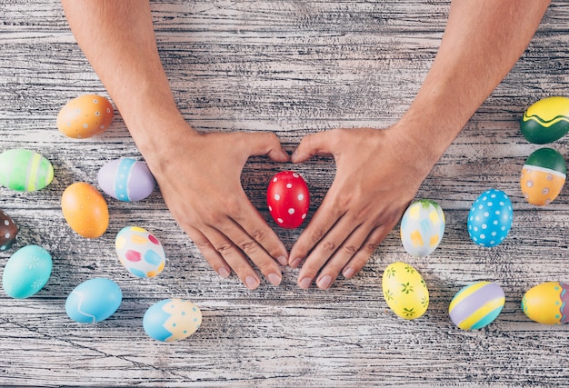 Hombre con forma de corazón con huevos de Pascua sobre fondo de madera.