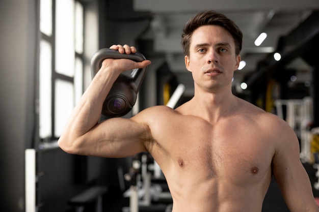 Hombre en forma entrenando con tiro medio de pesas rusas