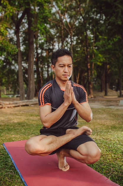 Foto gratuita hombre en forma haciendo yoga en el parque