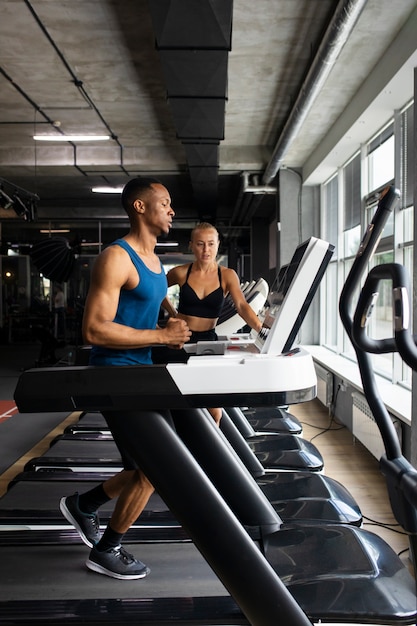 Foto gratuita hombre en forma de tiro completo entrenando en el gimnasio