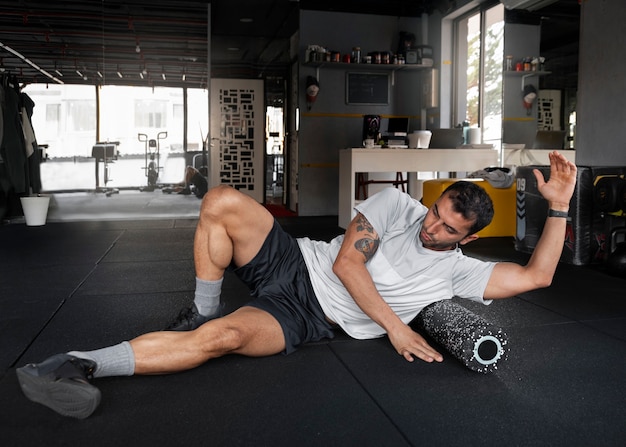 Foto gratuita hombre en forma de tiro completo entrenando en el gimnasio