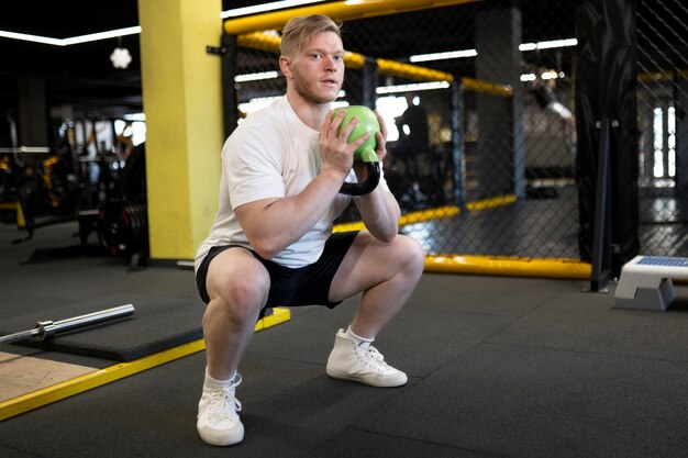 Hombre en forma de tiro completo entrenando con pesas rusas verdes