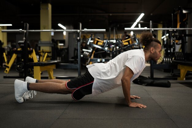 Hombre en forma de tiro completo haciendo burpee en el gimnasio