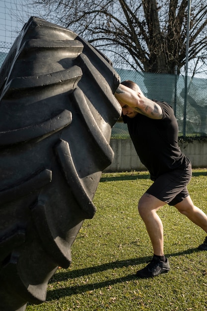 Hombre en forma de tiro completo haciendo ejercicio con rueda