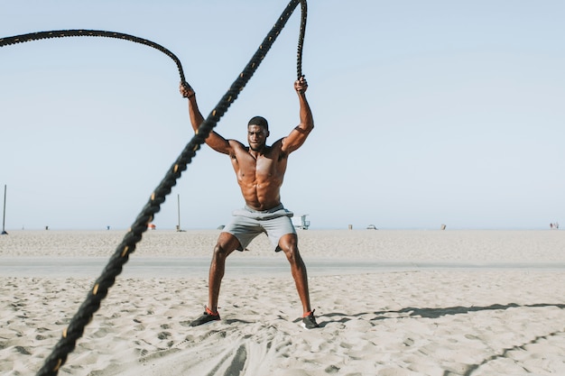 Hombre en forma trabajando con cuerdas de batalla