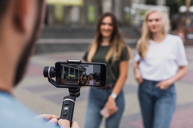 Hombre fotografiando mujeres con teléfono