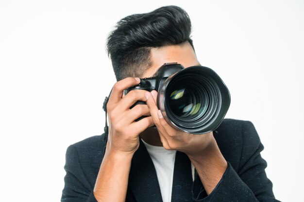 Hombre fotógrafo indio sosteniendo su cámara sobre un fondo blanco.