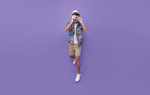 Hombre fotógrafo saltando está tomando fotos con cámara dslr estudio aislado fondo púrpura