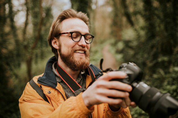 Hombre fotógrafo viendo sus fotos en la cámara al aire libre