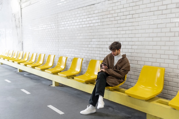 Hombre francés esperando el tren subterráneo y usando su teléfono inteligente