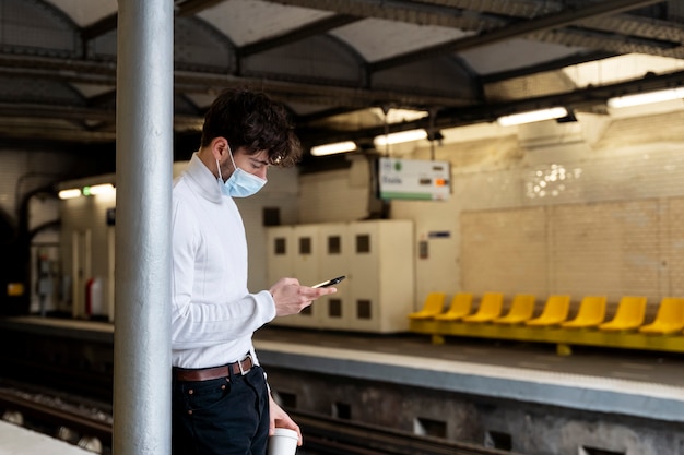 Hombre francés esperando el tren subterráneo y usando su teléfono inteligente