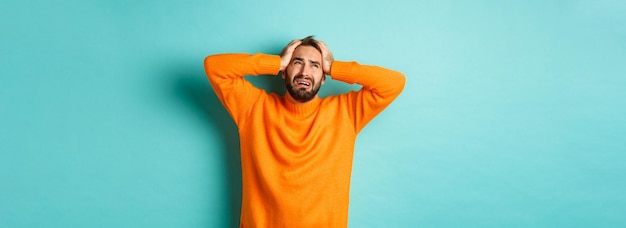 Hombre frustrado y desesperado con las manos en la cabeza mirando triste y angustiado de pie tenso sobre l