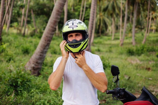 Hombre fuerte en el campo de la selva tropical con moto roja