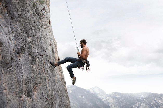 Foto gratuita hombre fuerte escalada en una montaña con equipo de seguridad