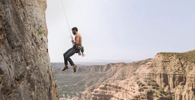 Foto gratuita hombre fuerte escalada en una montaña