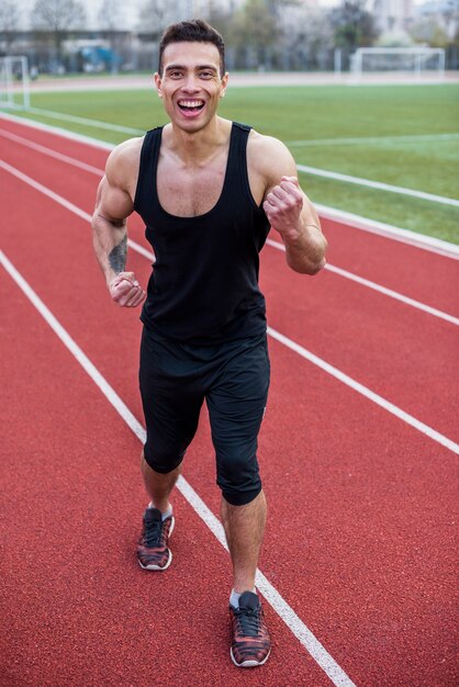 Hombre fuerte feliz celebrando su éxito en la pista de atletismo