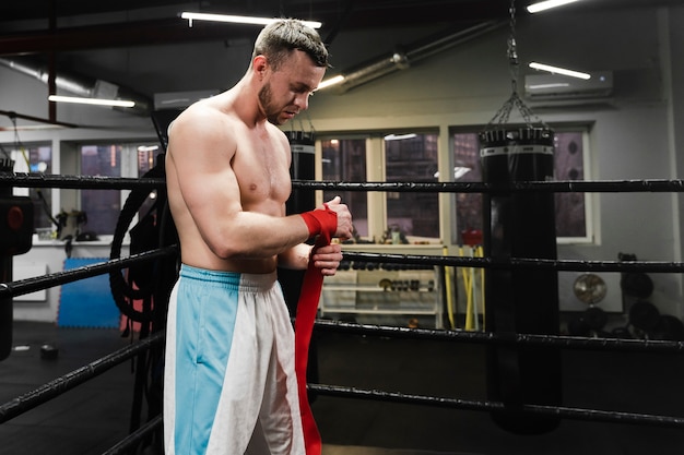 Hombre fuerte preparándose para entrenar en el ring de boxeo