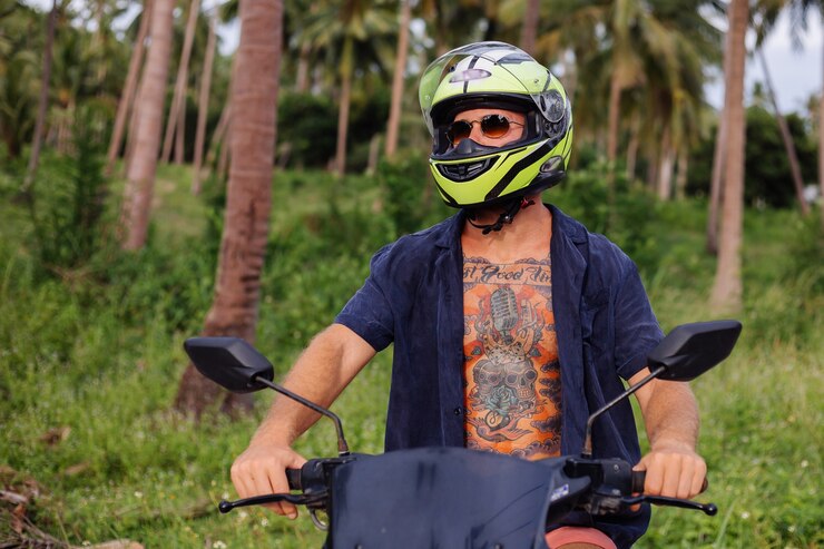 Foto gratuito hombre fuerte tatuado en un campo de la selva tropical con una motocicleta roja