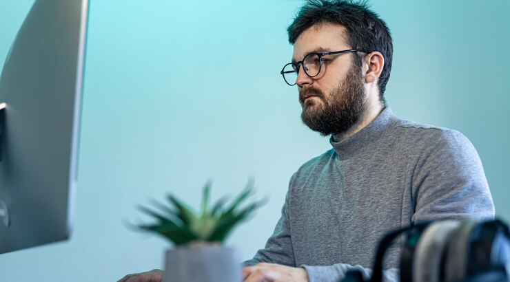 Foto gratuito un hombre con gafas y barba frente a una pantalla de computadora