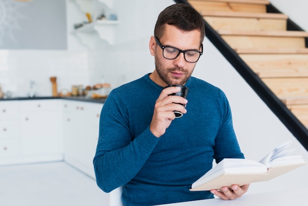 Foto gratuita hombre con gafas disfrutando de libro en casa