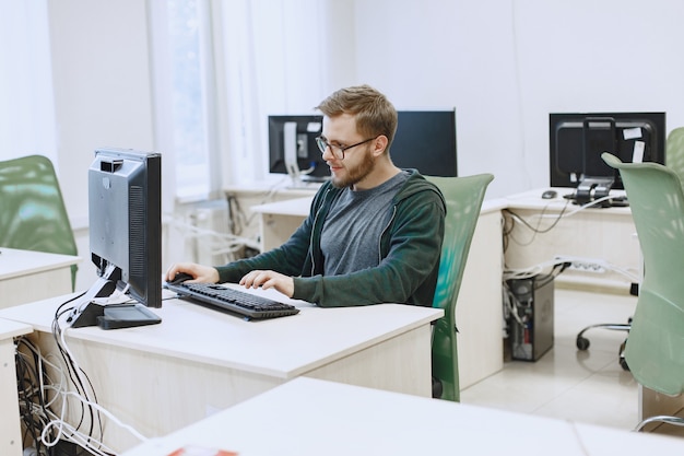 Hombre de las gafas. Estudiante en clase de informática. La persona usa una computadora.