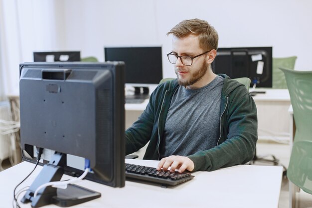 Hombre de las gafas. Estudiante en clase de informática. La persona usa una computadora.