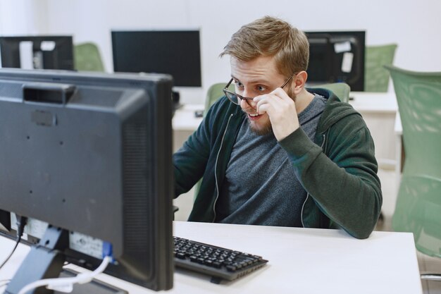 Hombre de las gafas. Estudiante en clase de informática. La persona usa una computadora.