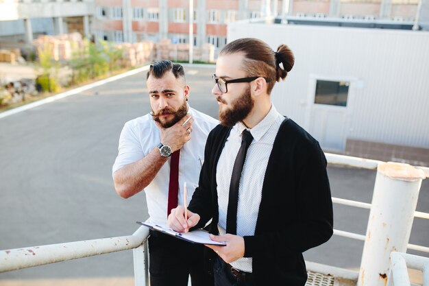 Hombre con gafas mirando una tablet con otro hombre de fondo