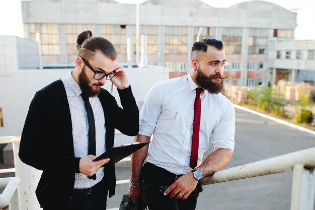 Hombre con gafas mirando una tablet con otro hombre de fondo