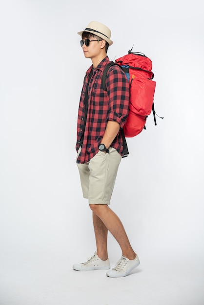 Un hombre con gafas sale a viajar, usa un sombrero y lleva una mochila.