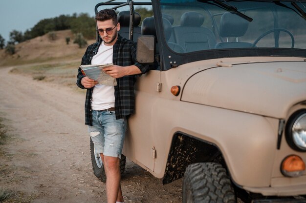 Hombre con gafas de sol comprobando el mapa mientras viaja en coche