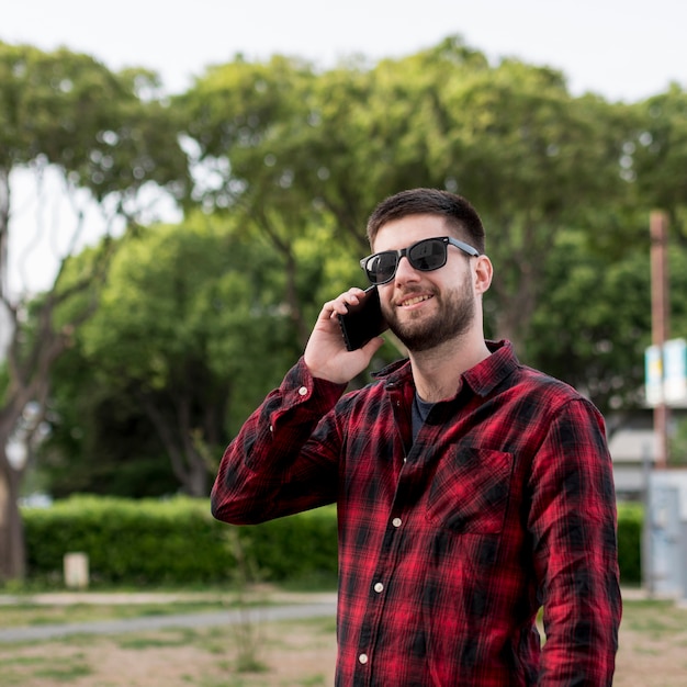 Hombre con gafas de sol comunicándose con smartphone.