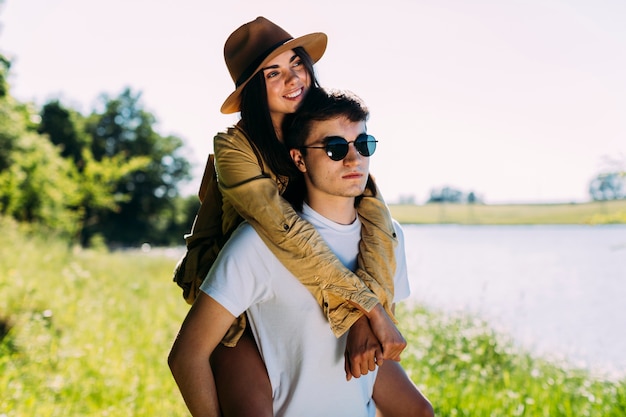 Foto gratuita hombre con gafas de sol dando a su novia a cuestas