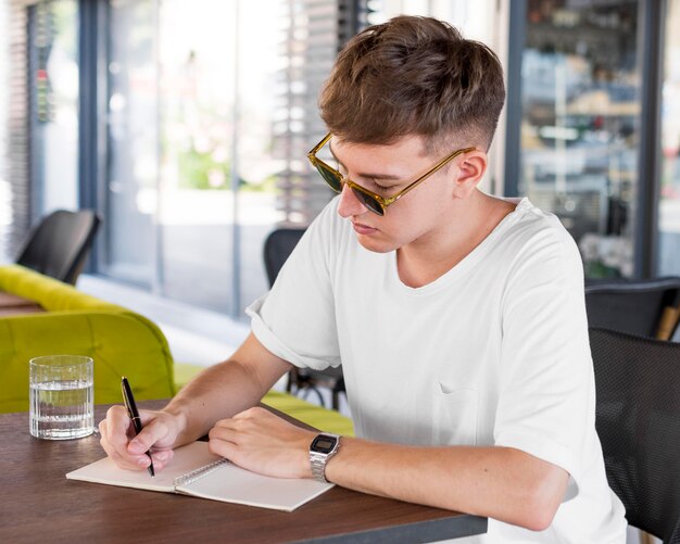 Hombre con gafas de sol escribiendo en el pub