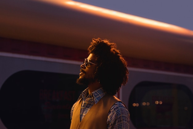 Hombre con gafas de sol posando en estilo retro por la noche