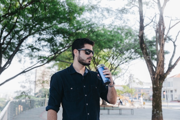 Hombre en gafas de sol con thermocup