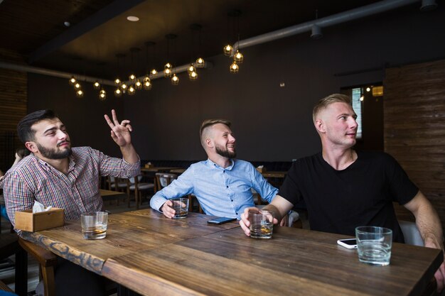 Hombre gesticulando mientras bebe charla con sus amigos en el bar