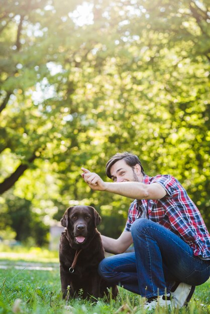 Hombre gesticulando mientras se divierte con su perro en el parque