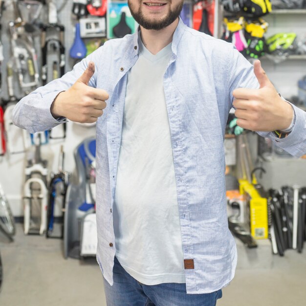 Hombre gesticulando pulgares arriba en el taller de bicicletas
