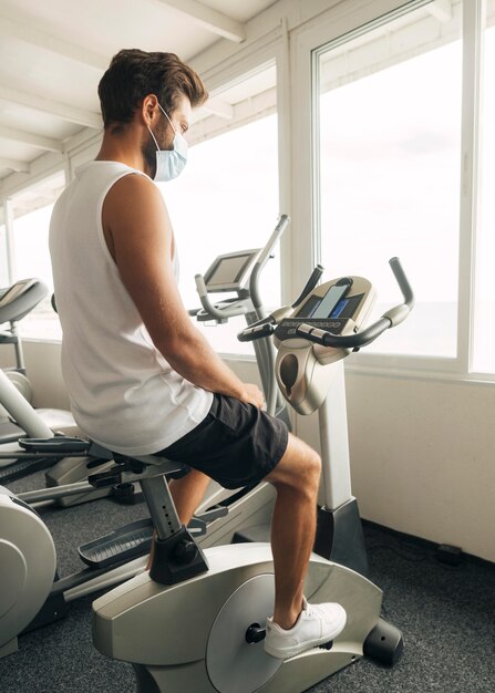 Hombre en el gimnasio trabajando con máscara médica