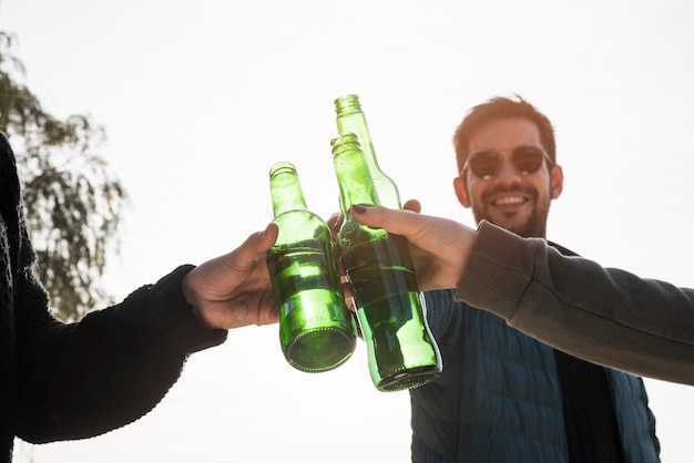 Hombre golpeando botella de cerveza con amigos