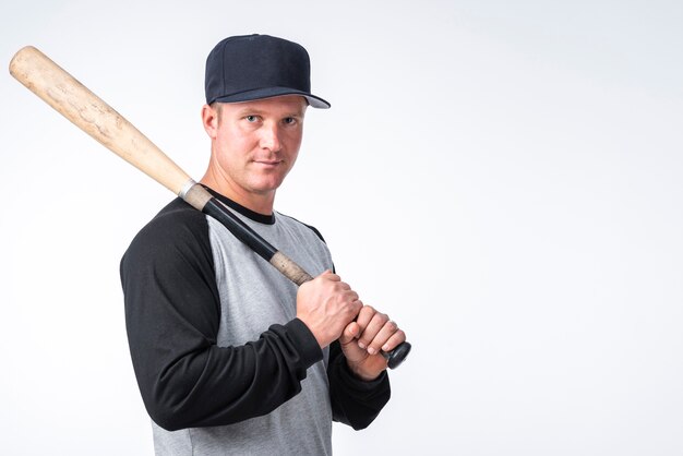 Hombre con gorra posando con bate de béisbol