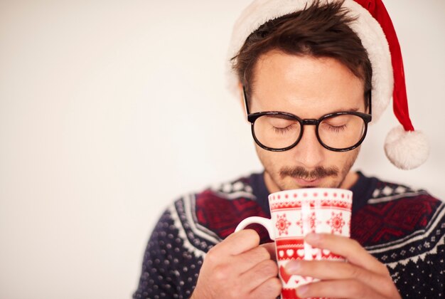 Hombre con gorro de Papá Noel bebiendo chocolate caliente