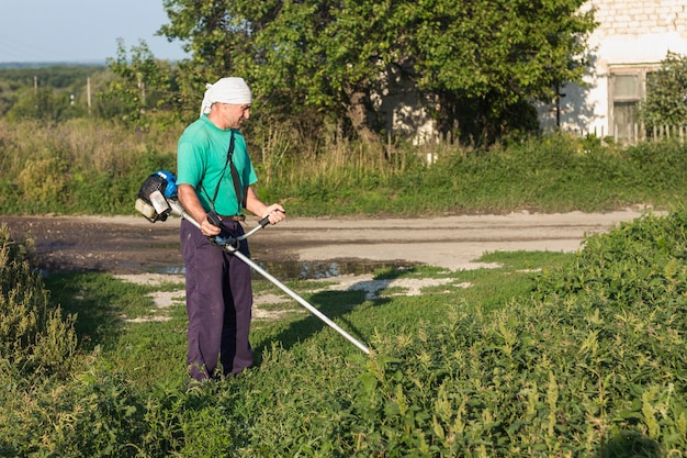 Hombre en la granja cosiendo hierba con cortacésped