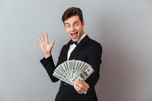 Hombre gritando emocionado en traje oficial con dinero.